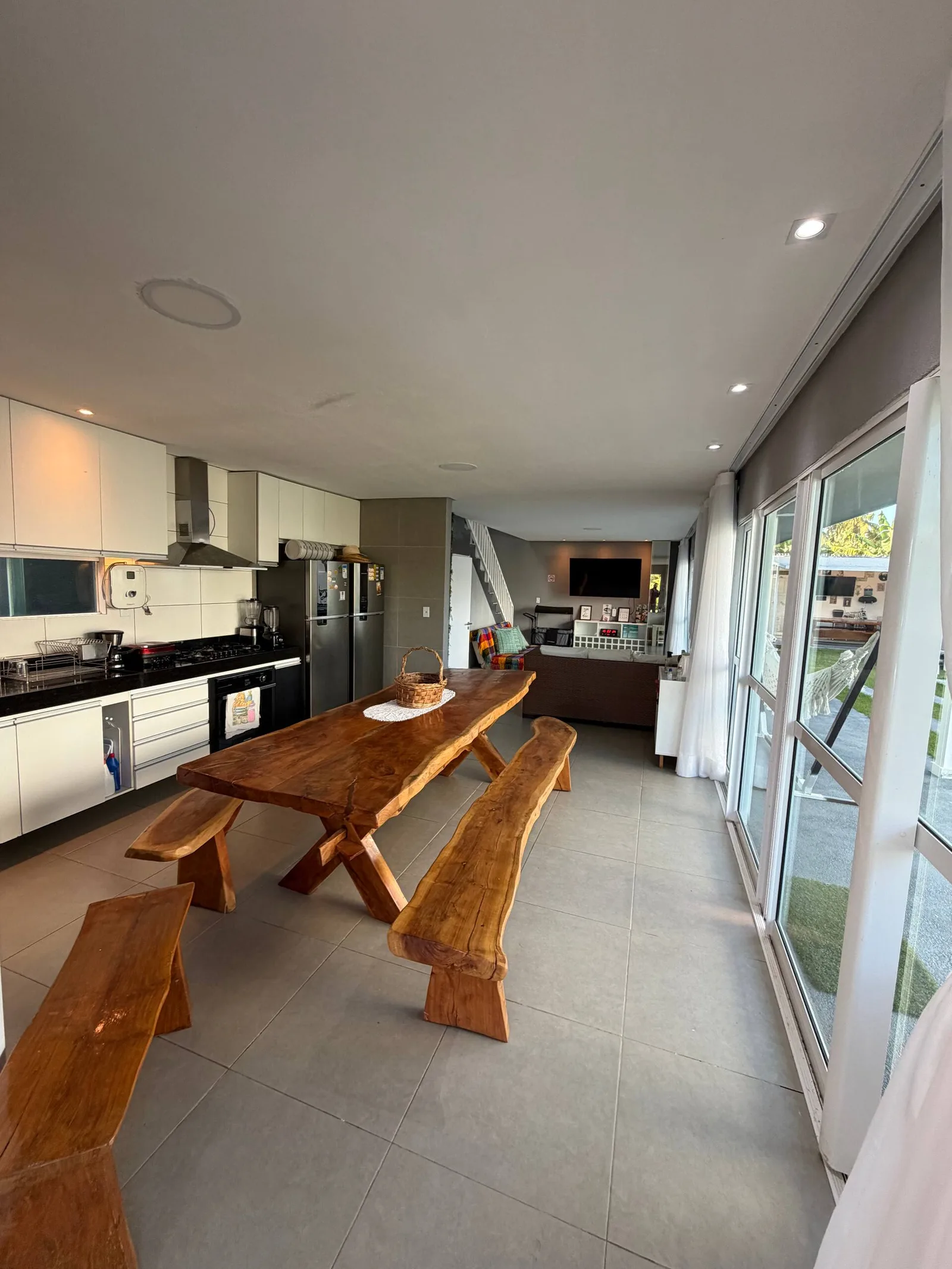 Mesa de jantar de madeira com bancos, cozinha ao fundo