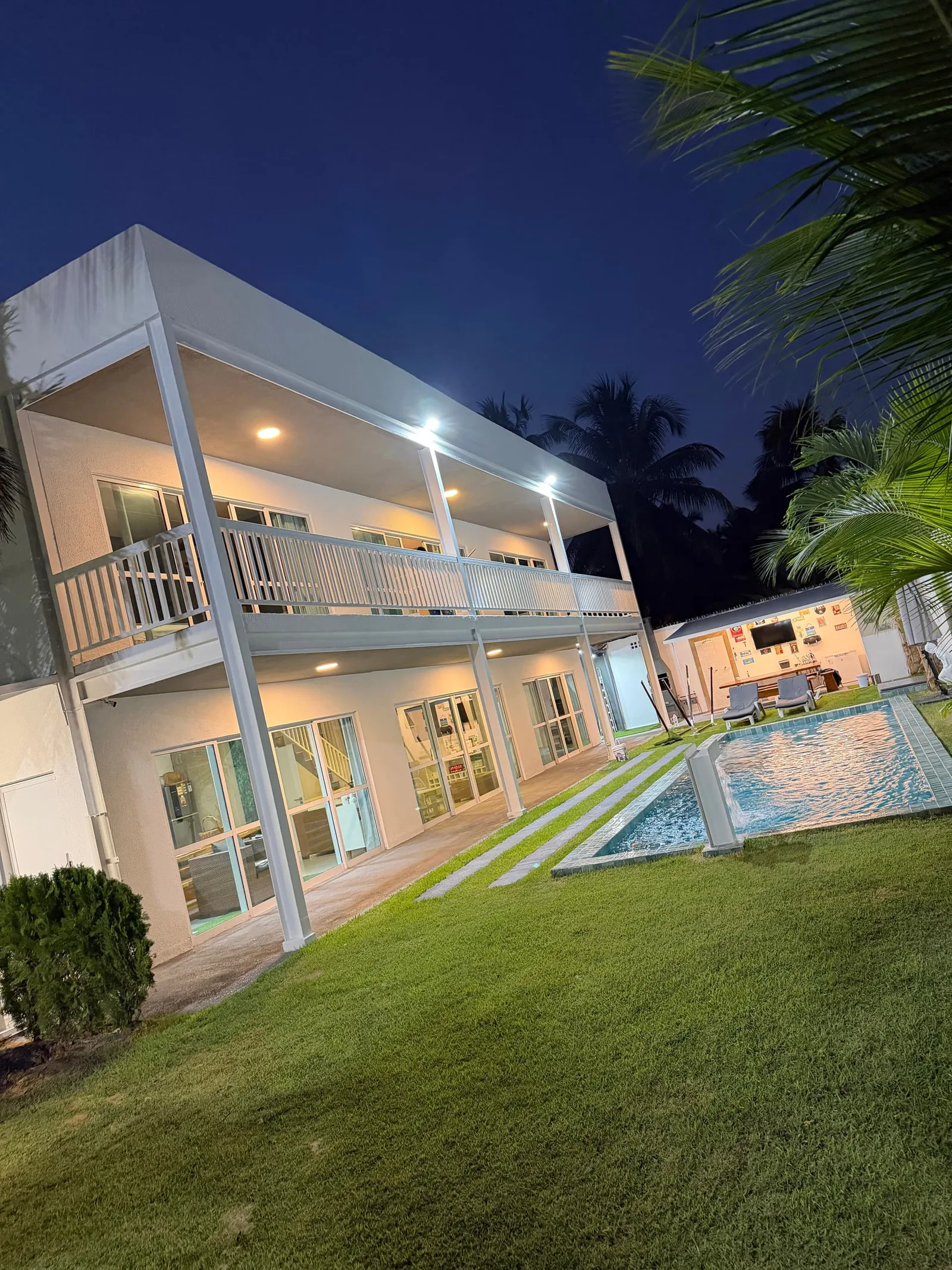 Casa Blanca Hibiscus iluminada ao anoitecer, piscina acesa em primeiro plano