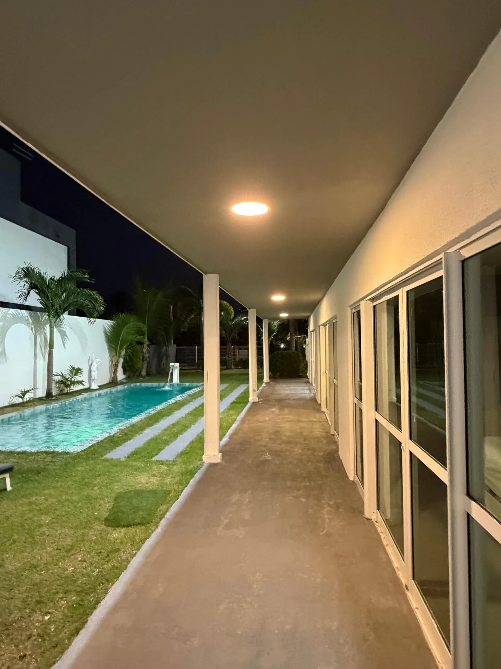 Piscina iluminada em azul à noite, vista do térreo