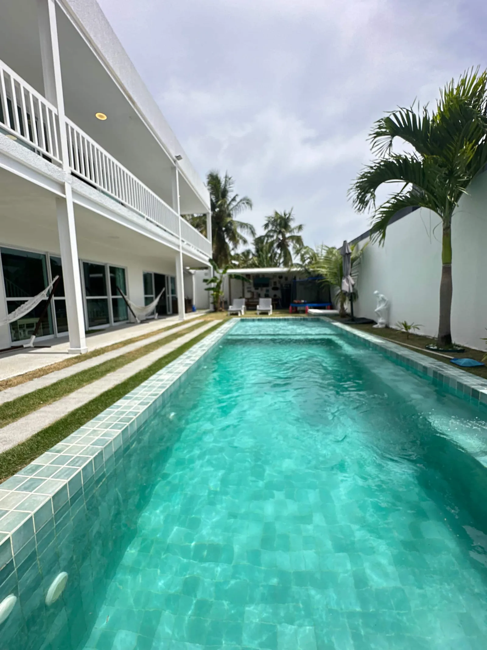 Casa de dois pavimentos com piscina em primeiro plano, dia ensolarado