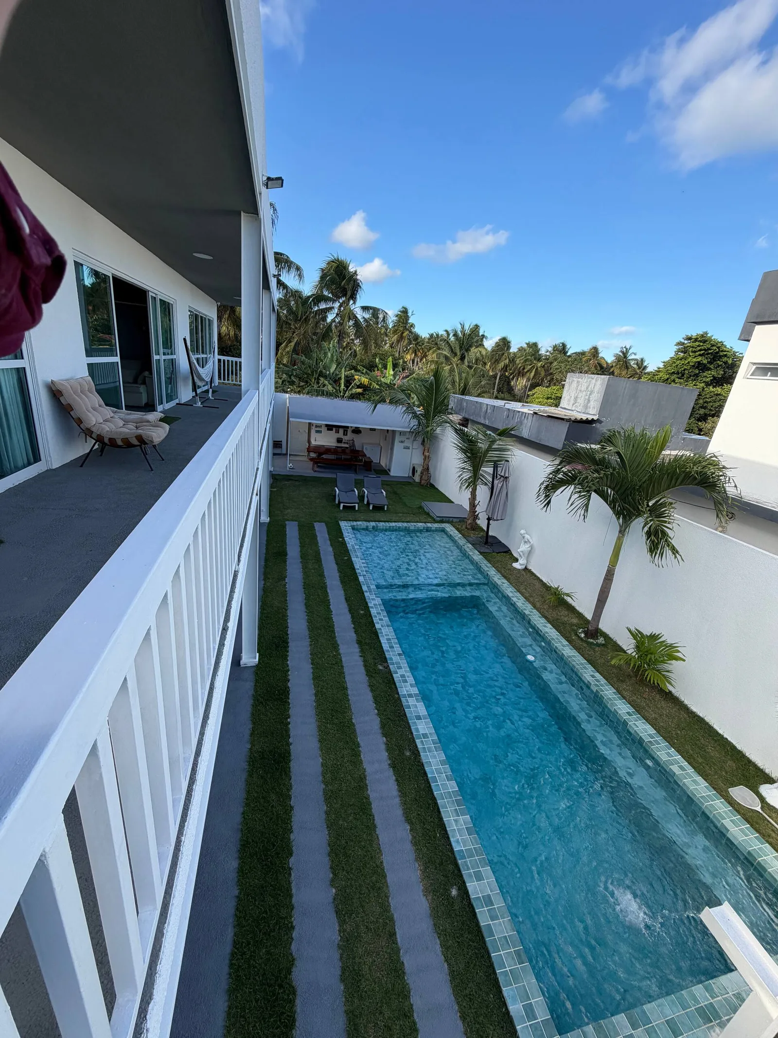 Vista aérea da piscina entre a casa e o muro do quintal, dia claro