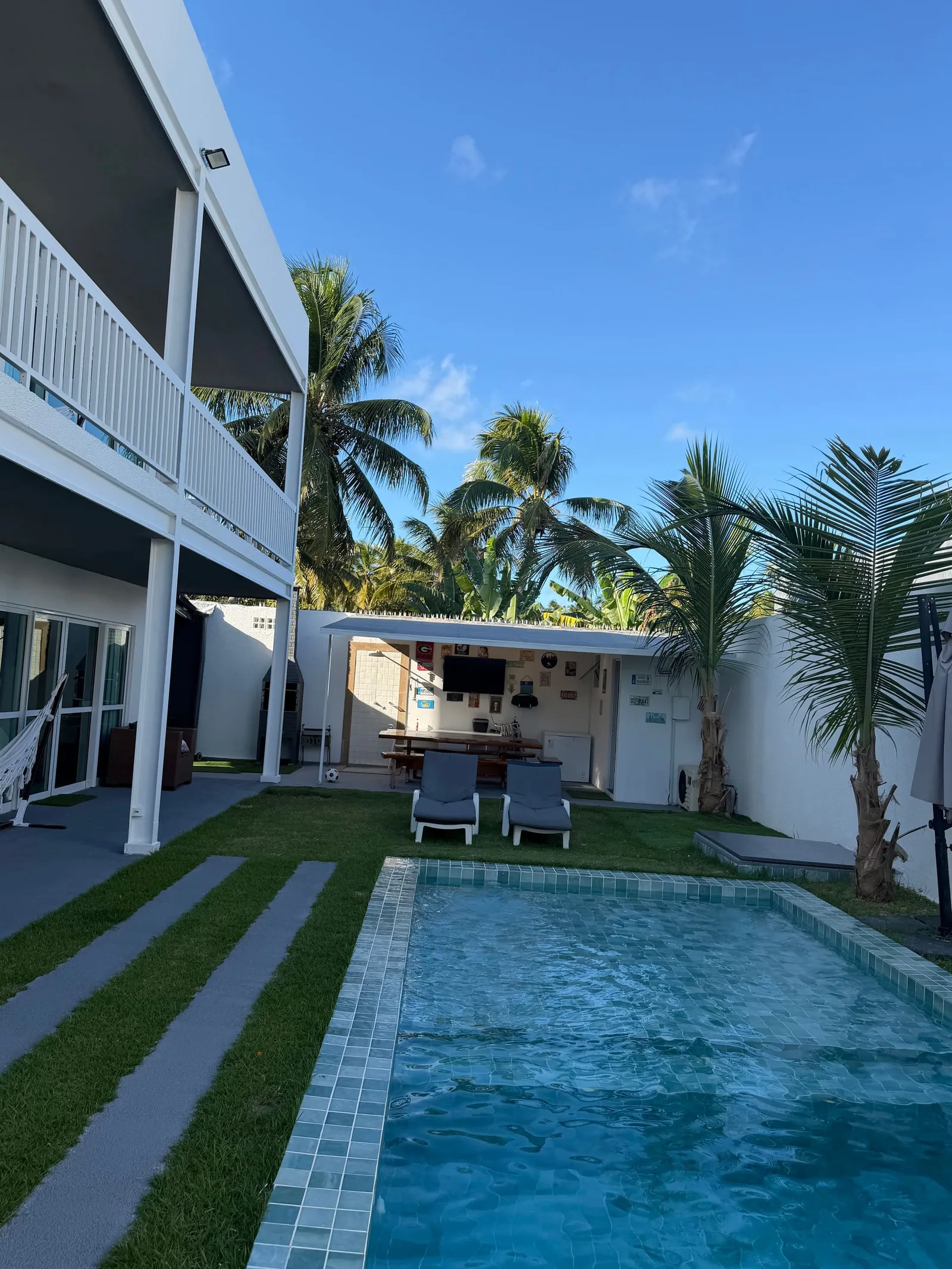Piscina vista de cima, com faixas de grama e calçada ao lado