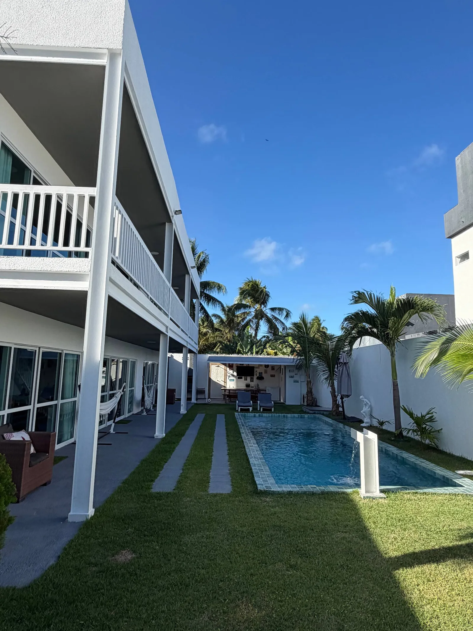 Piscina e área gramada vistas em ângulo, céu azul claro