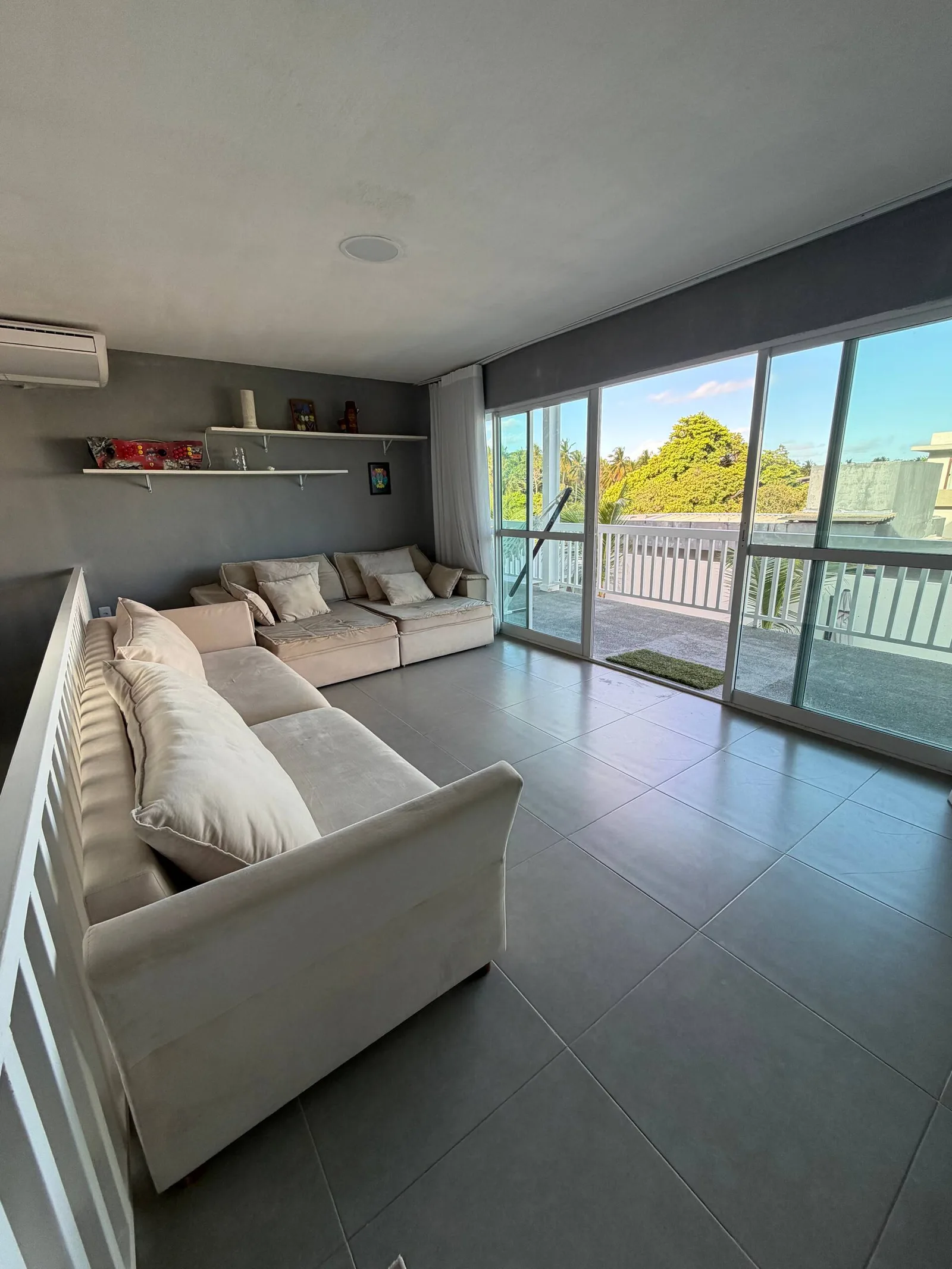Sala de estar com sofá branco e portas de vidro para a varanda