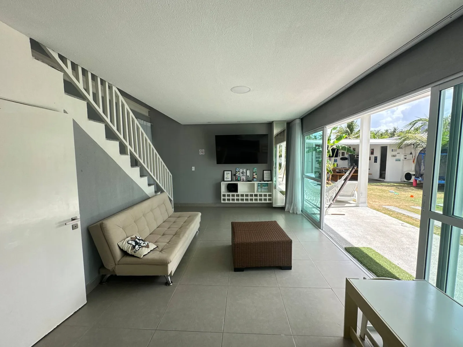 Sala ampla com sofás e mesa de jantar, vista para o jardim