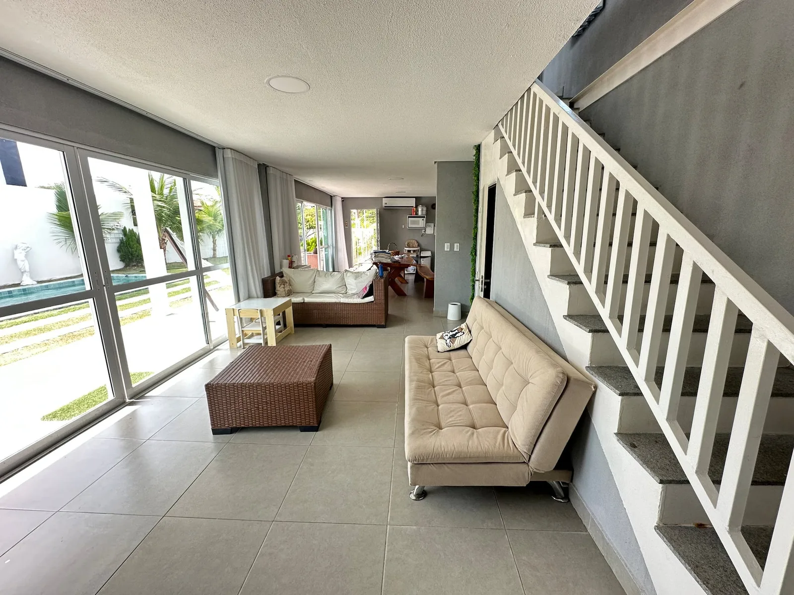 Sala de estar com sofás claros e escada de acesso ao segundo andar